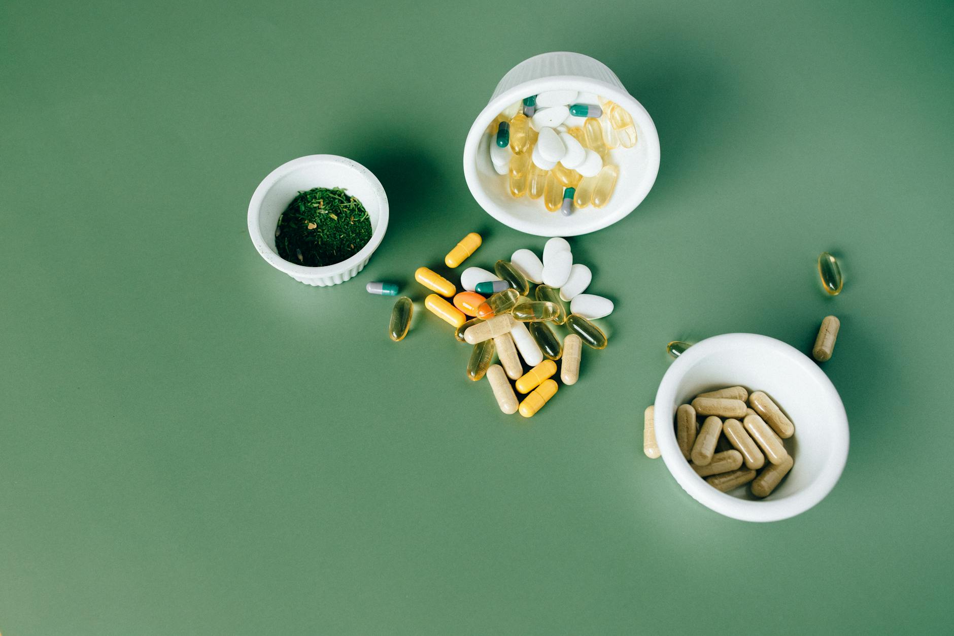 Various herbal and vitamin pills and capsules on a green surface. - vitamin d mood