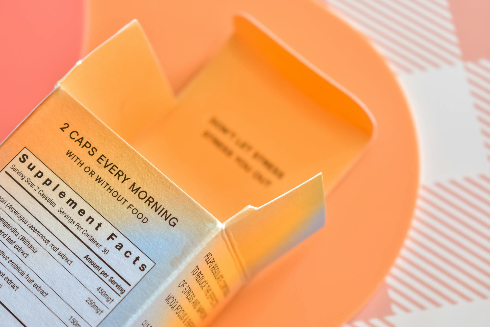 High angle view of an open supplement box on a peach-themed surface - vitamin d mood