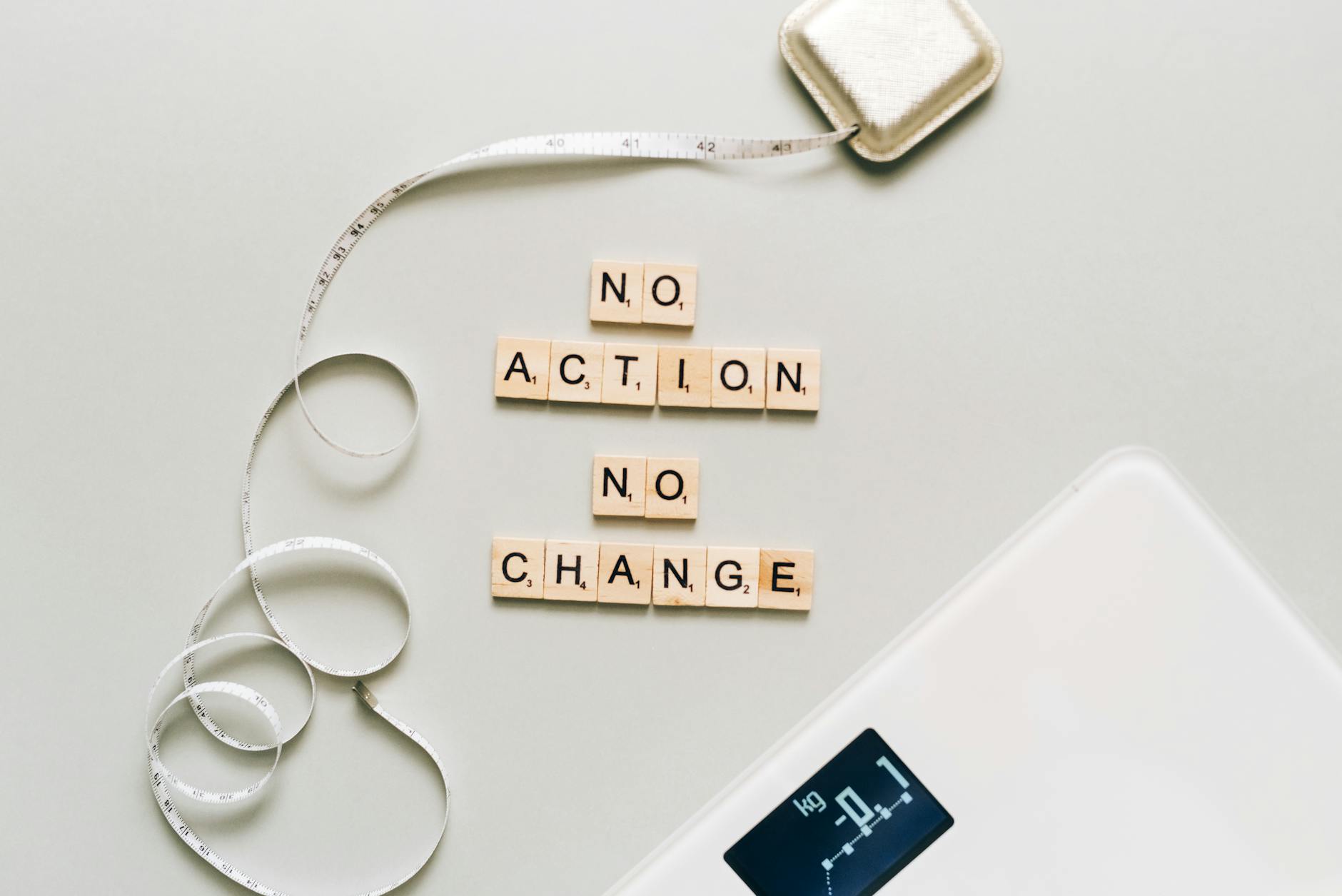 Motivational concept with scrabble tiles spelling no action no change alongside a measuring tape and scale. - weight loss motivation