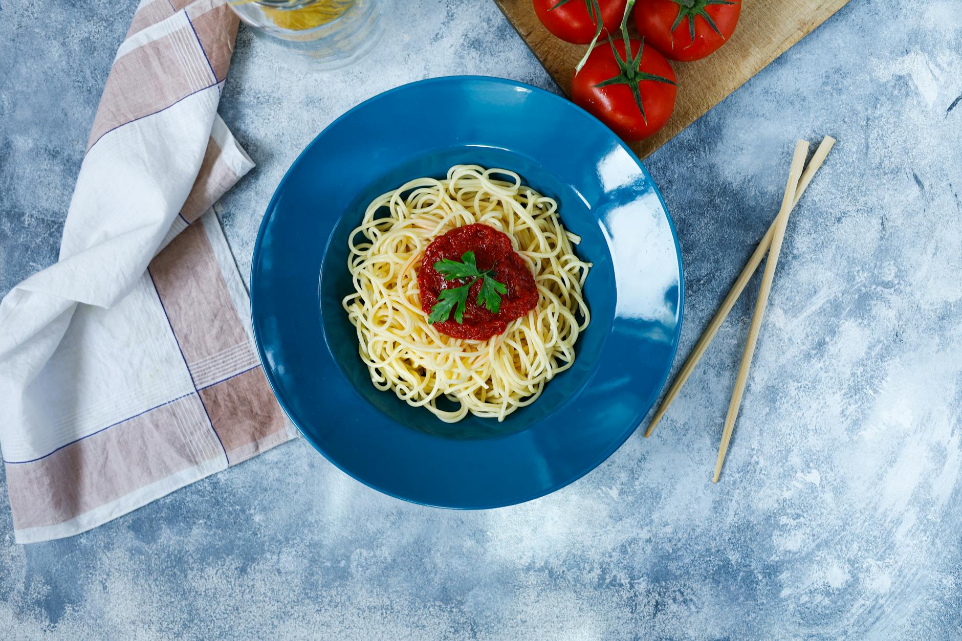 Top view of spaghetti with tomato sauce garnished with parsley, served on a blue plate. - weight watchers recipes