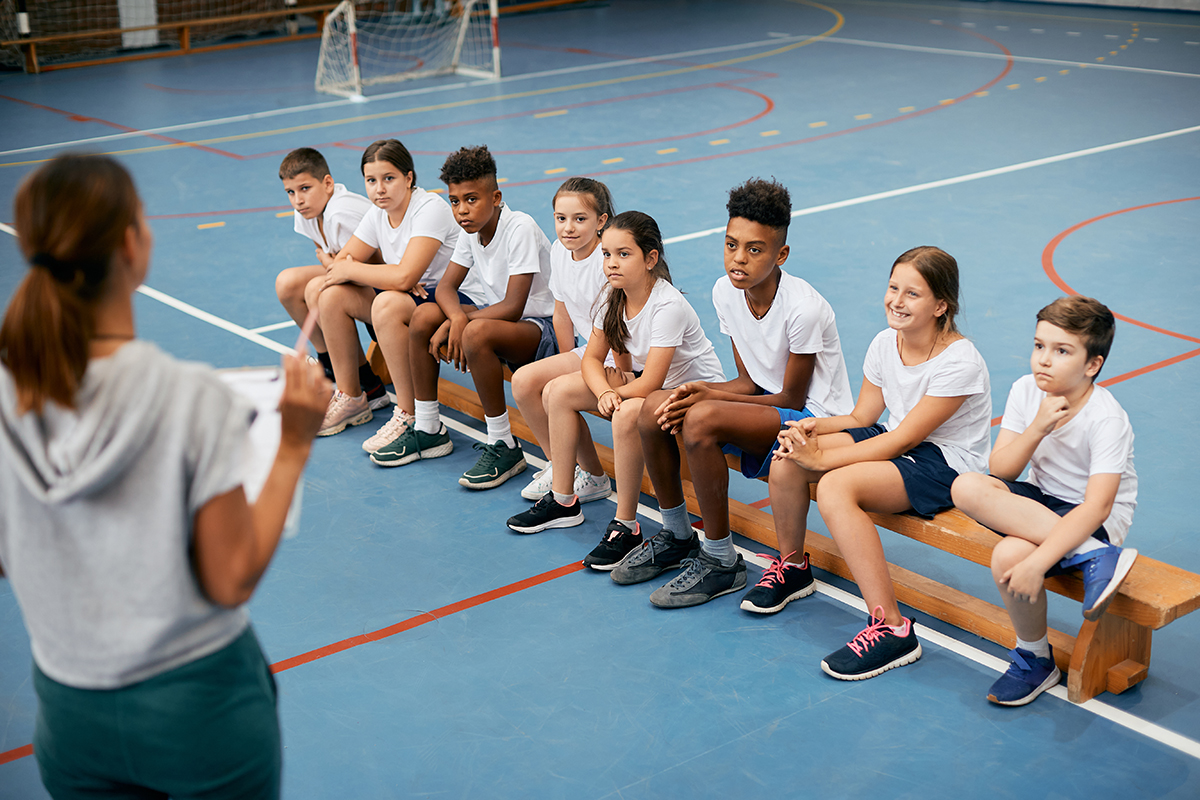 students having PE class with female coach at school gym