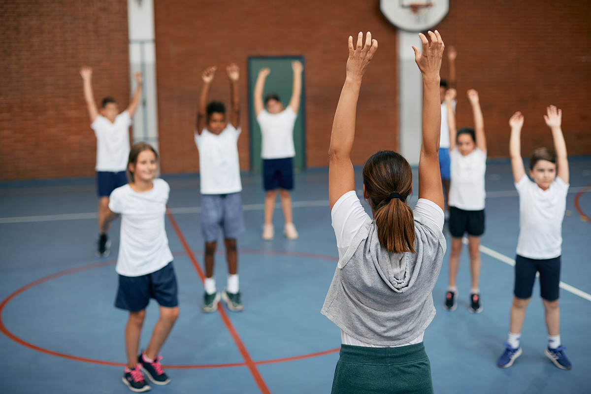 Students warming up during physical education at elementary school gym.