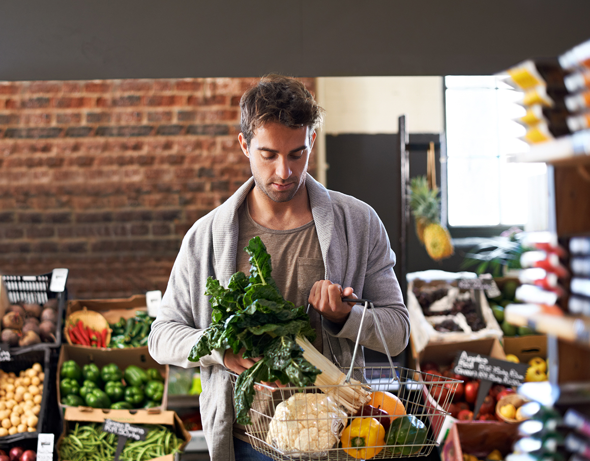Person thoughtfully choosing foods at a grocery store, demonstrating mindfulness in choosing a healthy diet