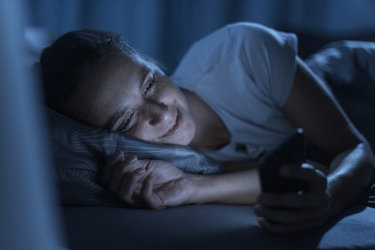 Person using a phone in bed, illustrating the disruptive role of technology in sleep
