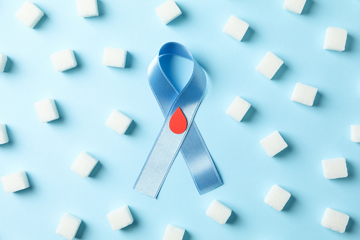 Diabetes awareness ribbon alongside sugar cubes on a blue background, symbolizing the collective journey and awareness of the diabetes community