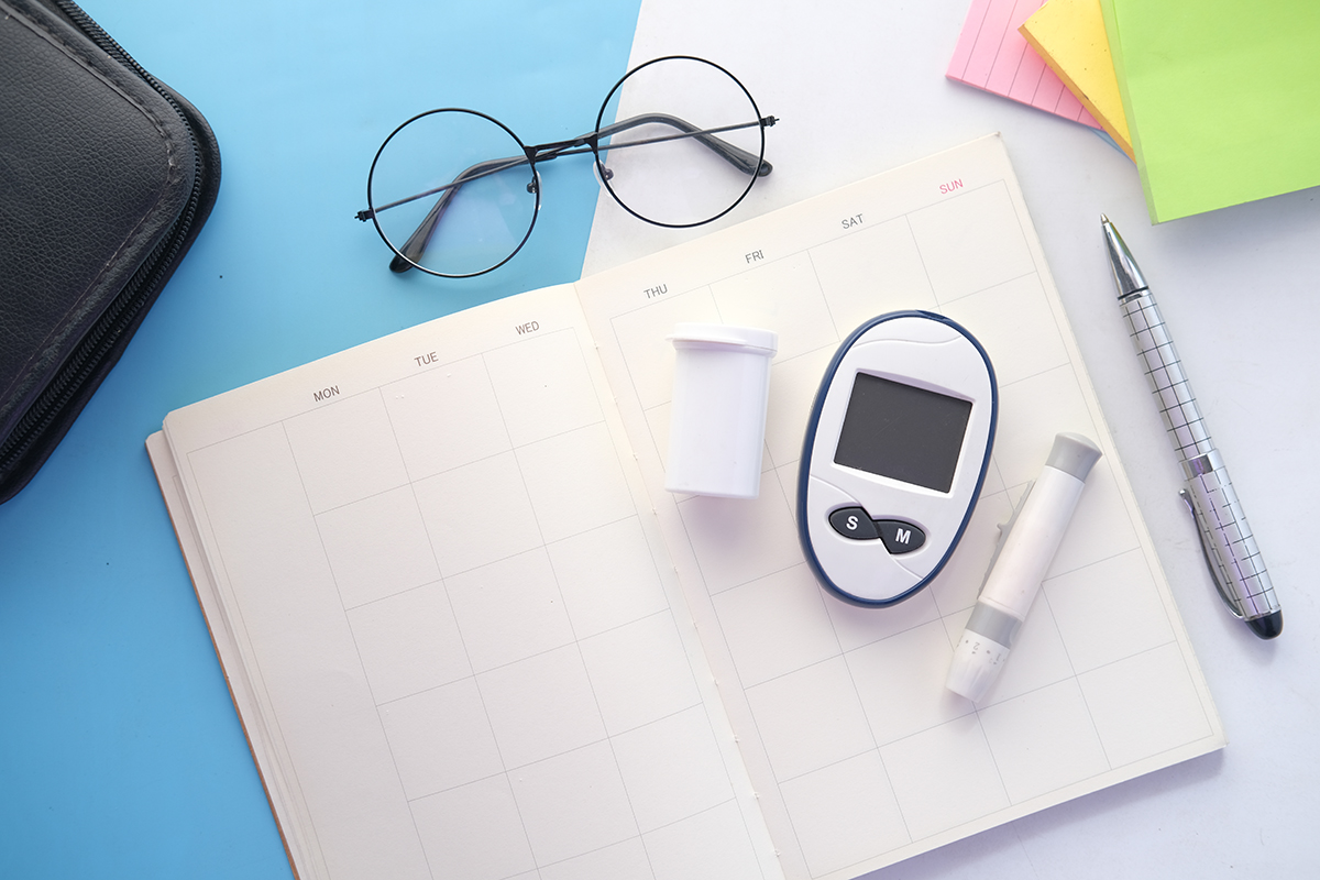 Diabetic measurement tools laid out on a planner on a table