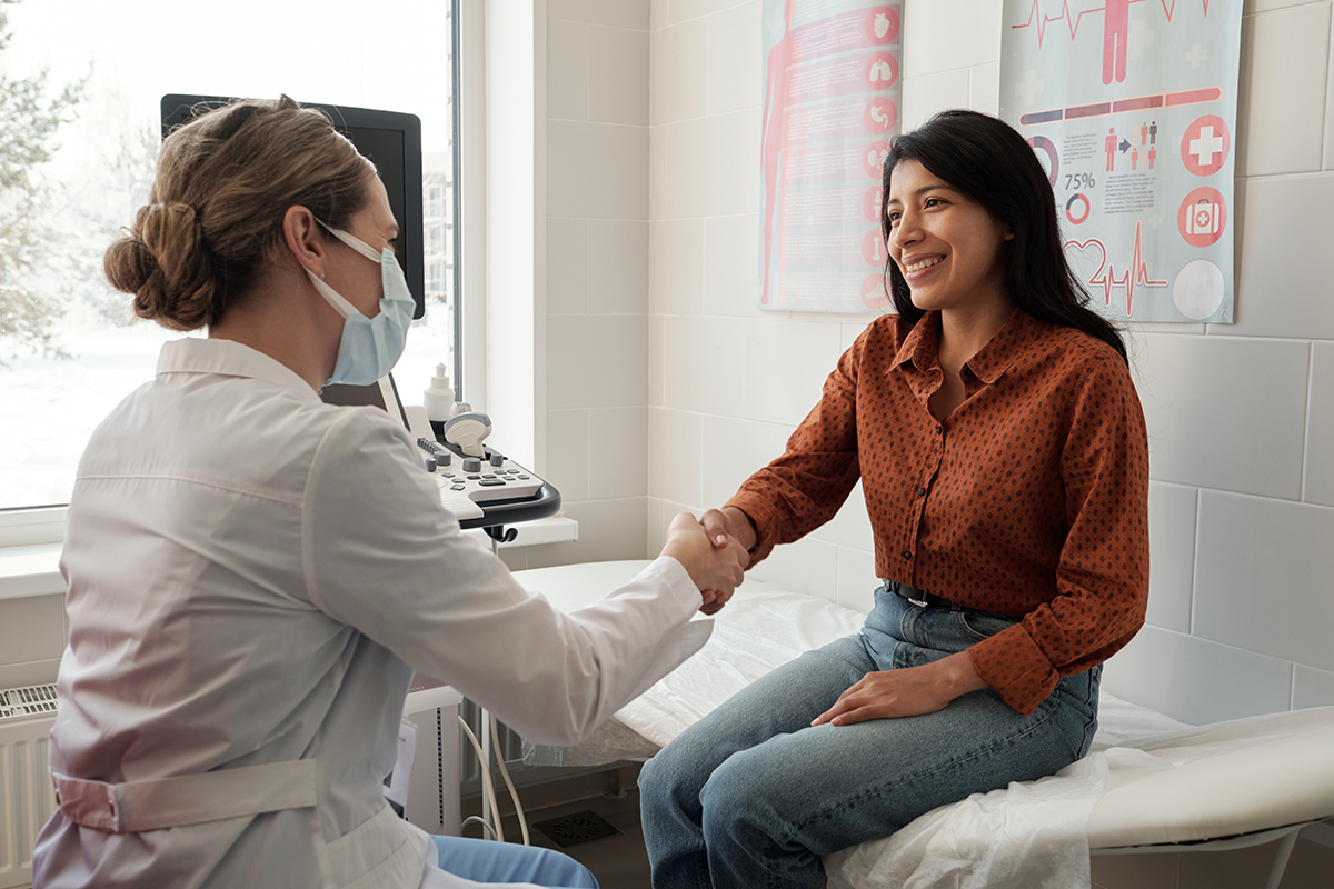 Female clinician congratulating a young, happy Hispanic patient, symbolizing the benefits of effective diabetes management